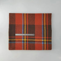 A folded Multicolor Plaid Mammoth Flannel Fabric by Longan Craft rests on a white surface, with a metal ruler on top for scale. This soft brushed polyester cotton flannelette is perfect for shirts and available by the yard.