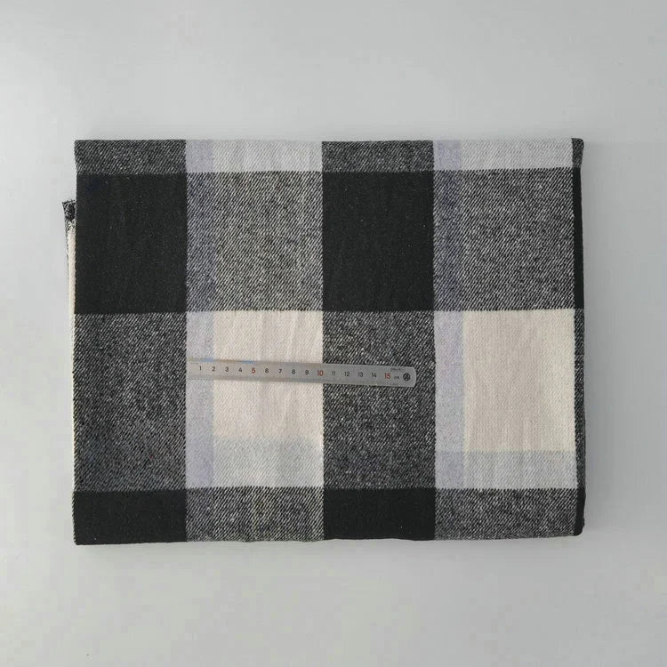 A folded Longan Craft Multicolor Plaid Mammoth Flannel Fabric by the yard lies on a light surface with a transparent ruler across the center, displaying the scale of this comfy brushed polyester cotton textile for shirts.