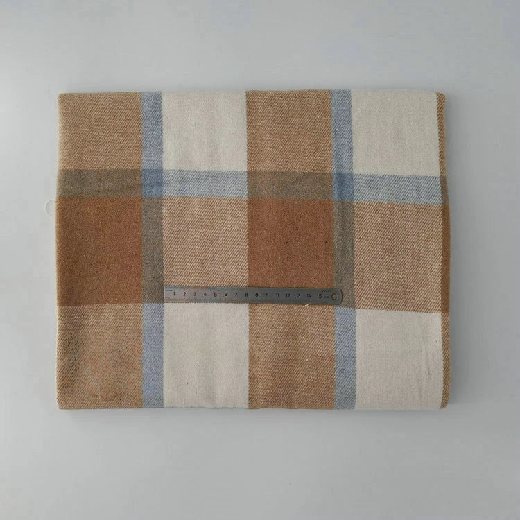 A folded Longan Craft Multicolor Plaid Mammoth Flannel Fabric by the yard rests on a light gray surface, with a metal ruler placed across the brushed polyester cotton textile for scale.