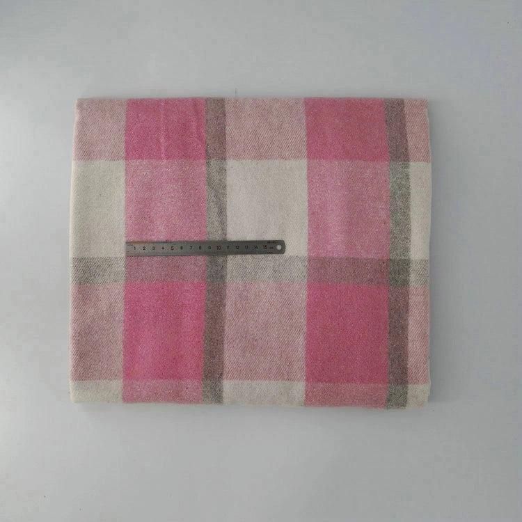 A folded Longan Craft Multicolor Plaid Mammoth Flannel Fabric is laid flat, displaying its pink, cream, and gray pattern. A black ruler rests across the brushed polyester-cotton material for scale. Ideal comfy flannelette for shirts, sold by the yard.