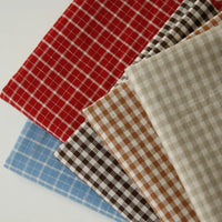 Five folded pieces of Longan Craft’s 100% Cotton Gingham Poplin Fabric By The Yard, in red, black, brown, beige, and blue—each featuring a classic small white checkered pattern—are displayed overlapping on a white background.