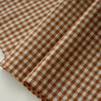 Close-up of the Longan Craft 100% Cotton Gingham Poplin Fabric By The Yard, featuring a classic brown and white multicolor yarn-dyed checkered pattern with evenly spaced squares. The premium soft poplin material is laid flat, highlighting its distinctive texture and weave—ideal for garment making.