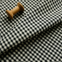 A wooden spool rests on neatly folded Longan Craft 100% Cotton Gingham Poplin Fabric by the yard, with the premium multicolor yarn-dyed checkered poplin pattern clearly visible.