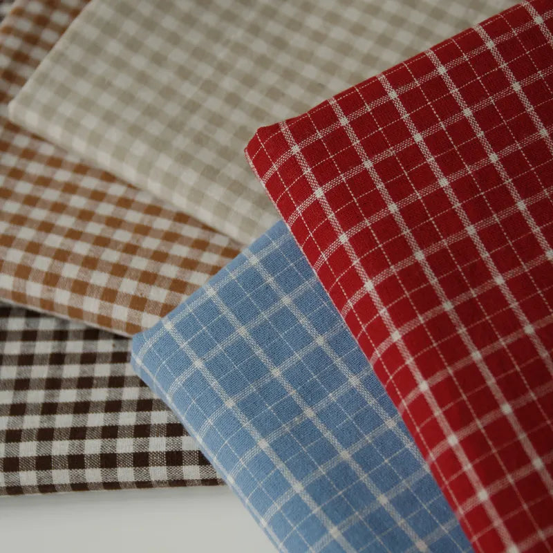 Five pieces of Longan Craft’s 100% Cotton Gingham Poplin Fabric, a premium multicolor yarn-dyed checkered material in brown, beige, blue, red, and dark brown hues, are neatly folded and arranged in a fan-like pattern on a white surface.