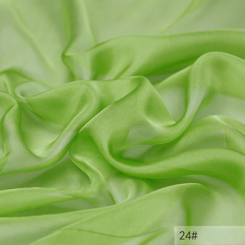 The Longan Craft 100 Mulberry Silk Chiffon Fabric By The Yard is a lightweight, translucent material in light green with a flowing texture and label 24# in the corner—ideal for colorful dresses.