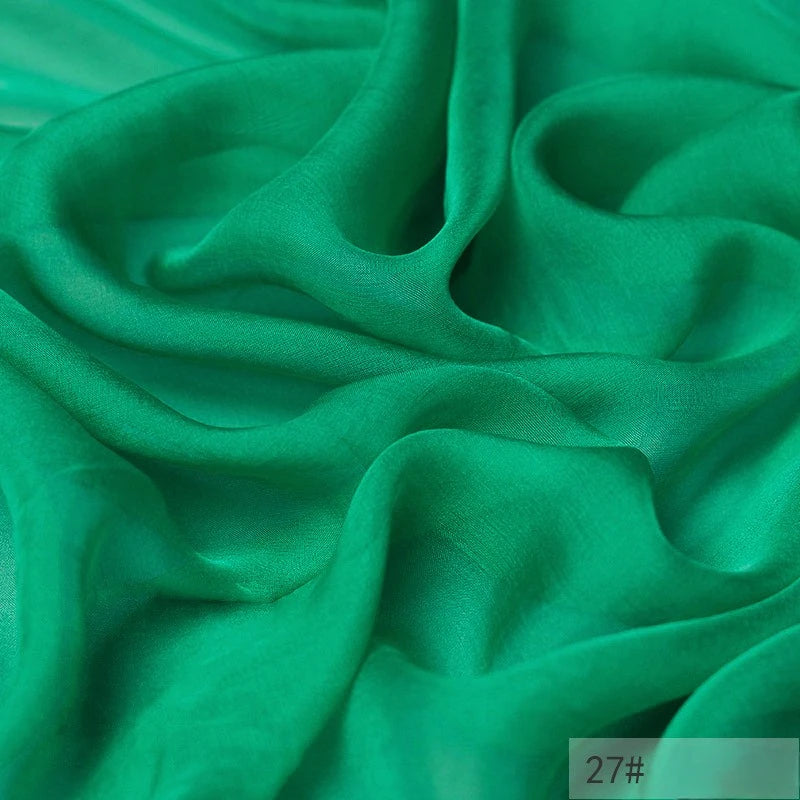 Bright green, semi-sheer 100 Mulberry Silk Chiffon Fabric by the yard from Longan Craft with soft, flowing folds and a smooth texture; “27#” appears in the bottom right corner. Ideal for colorful dresses.