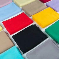 Neatly folded stacks of Longan Craft 100% Rayon Fabric By The Yard in solid colors—red, black, yellow, blue, beige, and purple—are arranged in a grid on a white surface. Ideal for soft viscose dressmaking and clothing projects.