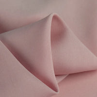 A close-up of Longan Craft's 100% rayon fabric by the yard in light pink shows its smooth, silky texture and gentle folds—ideal soft viscose material for dressmaking and clothing projects.