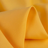 A close-up of Longan Craft’s 100% Rayon Fabric By The Yard highlights its silky-smooth, vibrant yellow surface. The lightweight, breathable viscose material displays gentle folds with subtle shadows and a soft texture—perfect for dressmaking.