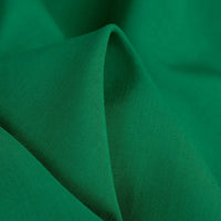 A close-up of Longan Craft's 100 Rayon Fabric By The Yard reveals its vibrant green color, lightweight softness, and smooth texture—ideal as a breathable, solid color viscose material for comfortable dressmaking and clothing projects.