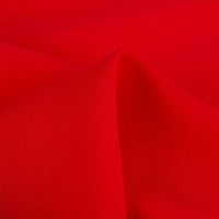 A close-up of Longan Craft's 100% rayon fabric by the yard shows its smooth, vibrant red viscose material with soft folds and gentle shadows, highlighting the texture perfect for dressmaking and solid color clothing projects.