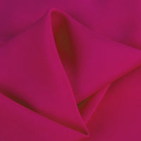 A close-up of Longan Craft’s 100% rayon fabric shows its vibrant magenta color, silky-smooth texture, and soft folds—ideal for dressmaking. Available by the yard as solid viscose clothing material.