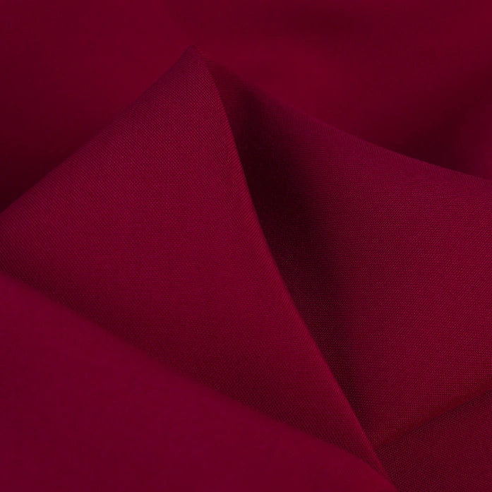Close-up of smooth, folded maroon 100% rayon fabric by Longan Craft, featuring a solid color and subtle sheen. This soft viscose dressmaking textile is perfect for clothing projects and is available by the yard.