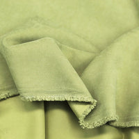 Longan Craft’s Multi Color Microsuede Polyester Peachskin Fabric by the yard features a soft, brushed peach skin texture with a cozy feel—displayed here in light green, draped and slightly folded to show its subtle fringe edge.