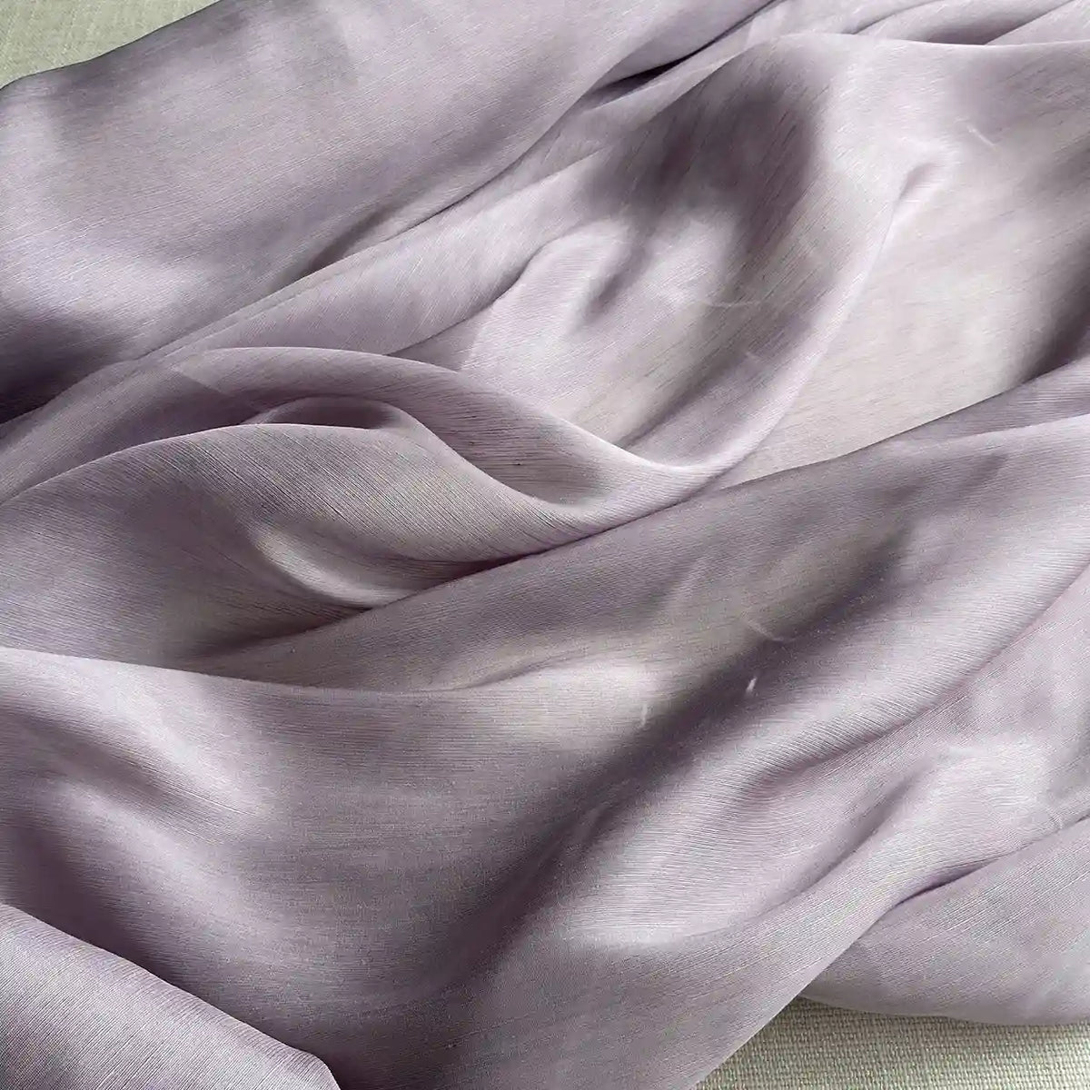 A close-up of Longan Craft's 14 Momme Linen Silk Fabric—vibrant organza mulberry silk material in soft light purple, featuring a smooth, slightly shiny texture with gentle folds. Ideal silk for summer and sold by the yard.
