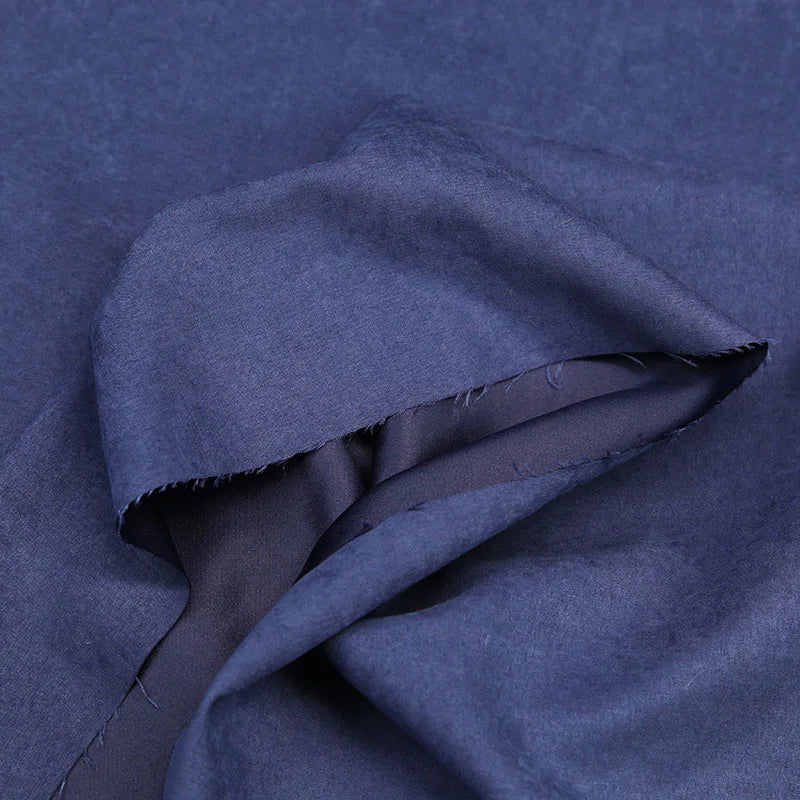 A close-up of Longan Craft’s Multi Color Microsuede Polyester Peachskin Fabric by the yard, featuring brushed peach skin texture, a folded edge, and unfinished seam with loose threads. Perfect cozy material for clothing.