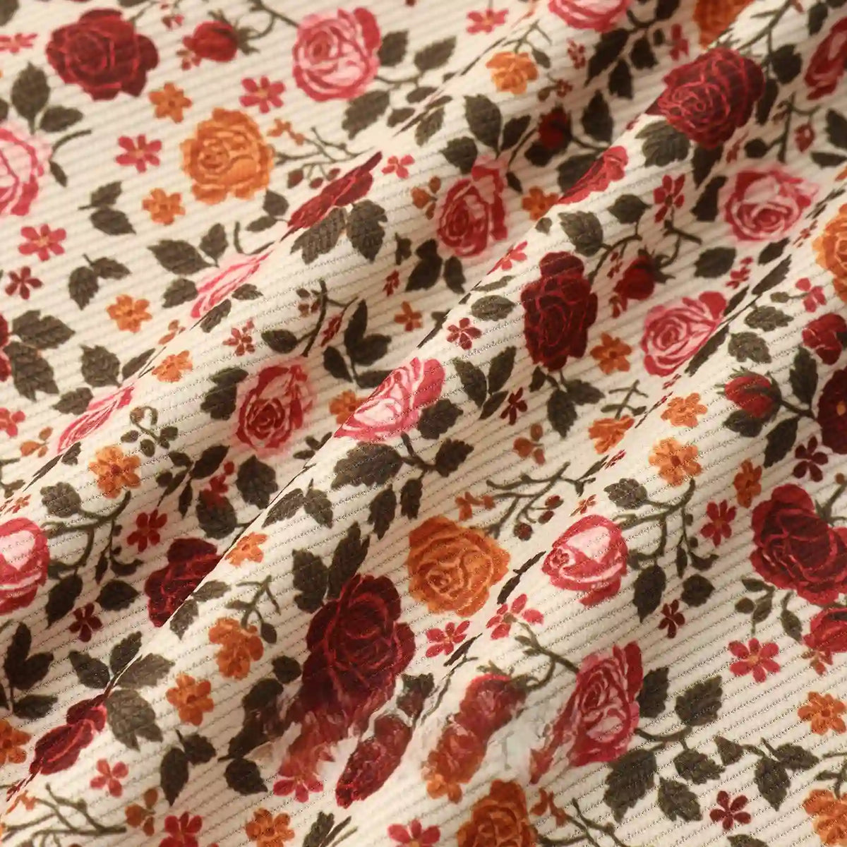 Longan Craft's 16 Wale Floral Printed Corduroy Fabric by the yard features a cream base, ribbed texture, and vibrant roses in red, pink, and orange with green leaves—premium material ideal for casual wear.