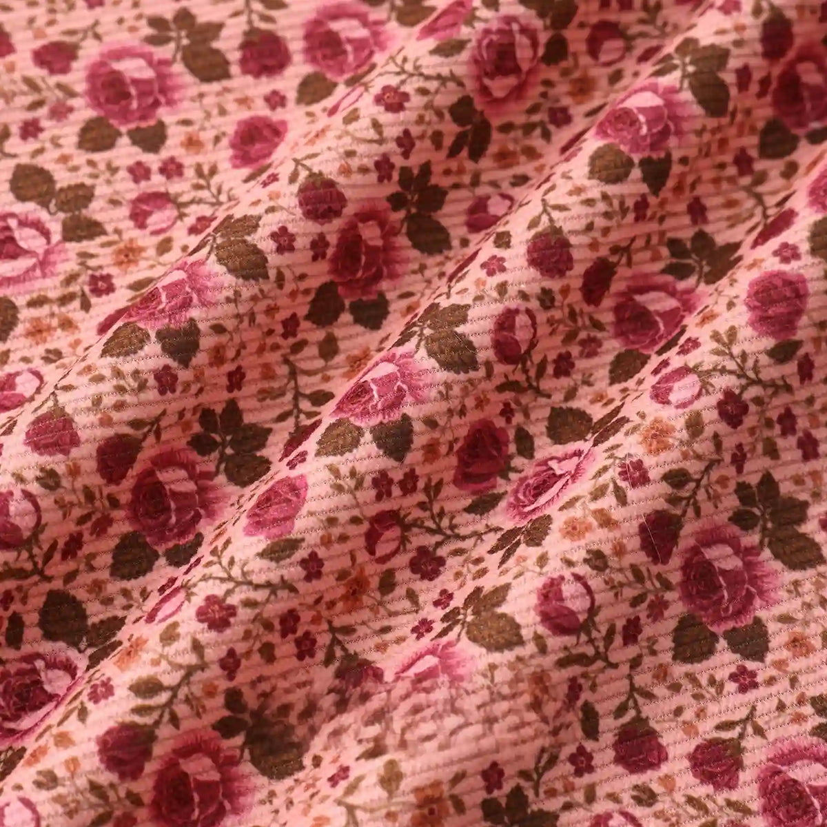 A close-up of Longan Craft’s 16 Wale Floral Printed Corduroy Fabric by the Yard shows its colorful, fine wale texture with red roses and green leaves—premium corduroy perfect for casual wear.