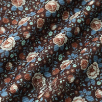 Close-up of Longan Craft 16 Wale Floral Printed Corduroy Fabric By The Yard, showing cream, blue, and rusty red roses with green leaves. Gentle folds add soft shadows and texture to this colorful fine wale premium corduroy textile.