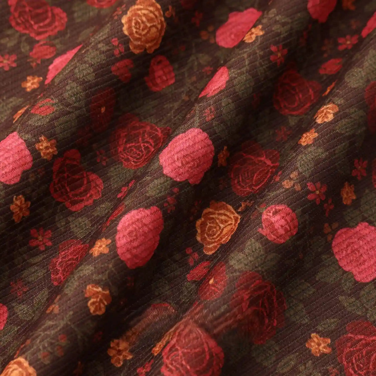 Close-up of Longan Craft's 16 Wale Floral Printed Corduroy Fabric by the yard, featuring colorful red and orange rose blooms on fine wale corduroy; premium texture ideal for casual wear and crafting projects.
