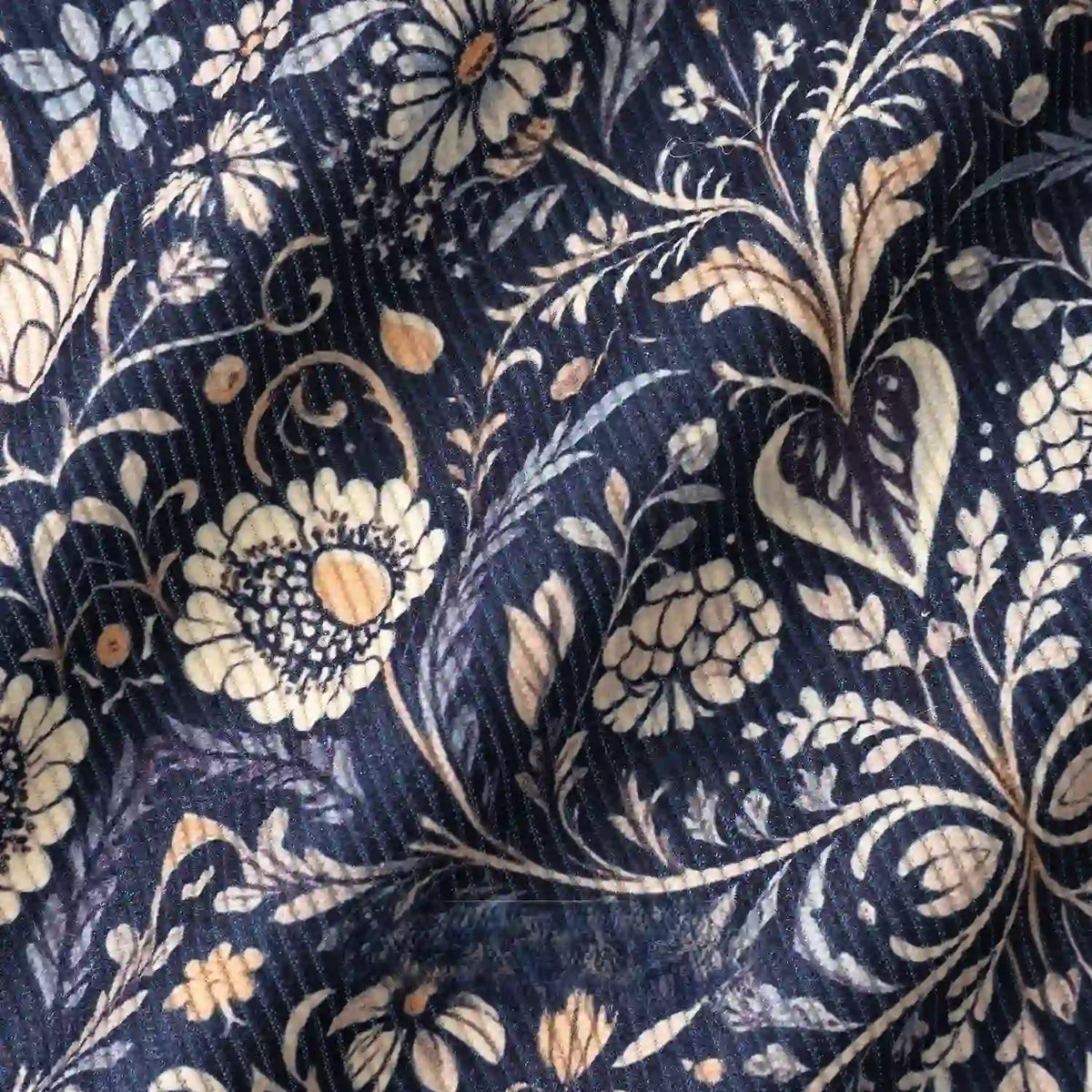 Close-up of Longan Craft's 16 Wale Floral Printed Corduroy Fabric by the yard, featuring detailed white, cream, and beige flowers, leaves, and vines on dark blue premium fine wale corduroy with a slightly wrinkled texture.