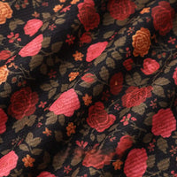 Close-up of Longan Craft 16 Wale Floral Printed Corduroy Fabric by the yard, featuring a textured black base with vibrant red, orange, and green floral prints. Fine wale corduroy material ideal for casual wear; gentle folds highlight its premium texture.