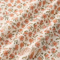 A close-up of Longan Craft’s 16 Wale Floral Printed Corduroy Fabric shows cream-colored, textured fine wale material with small orange and green patterns—premium corduroy by the yard for casual wear.
