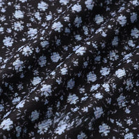 Longan Craft 16 Wale Floral Printed Corduroy Fabric by the Yard features a premium black corduroy with fine wale texture and light blue & white floral clusters, perfect for casual wear. Subtle wrinkles add depth to this colorful textile.