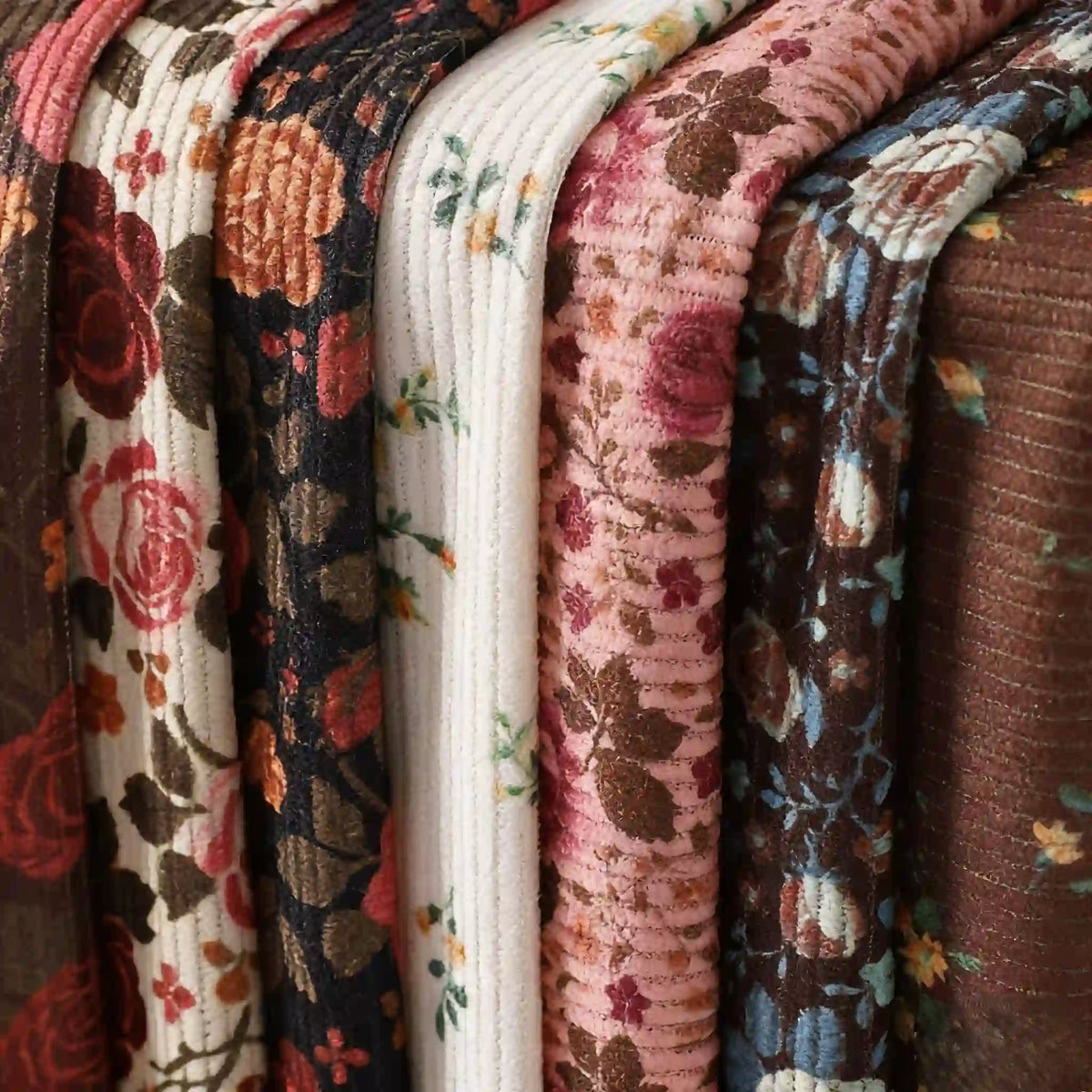 Rows of Longan Craft 16 Wale Floral Printed Corduroy Fabric by the yard, featuring colorful patterns in red, pink, brown, white, and blue, are neatly arranged side by side as premium material for casual wear.