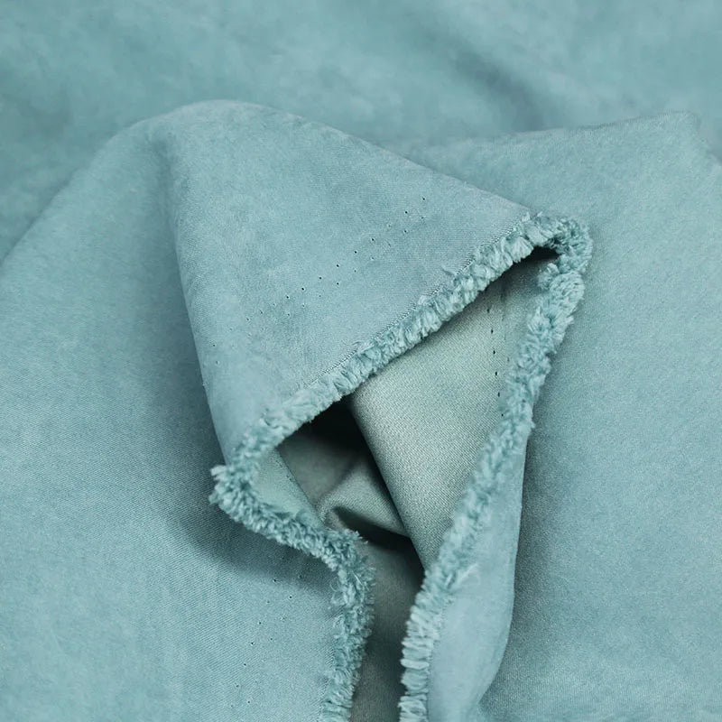 Close-up of folded Multi Color Microsuede Polyester Peachskin Fabric by the yard from Longan Craft, showing its soft, brushed peach skin texture and slightly frayed edge—ideal cozy material for clothing.