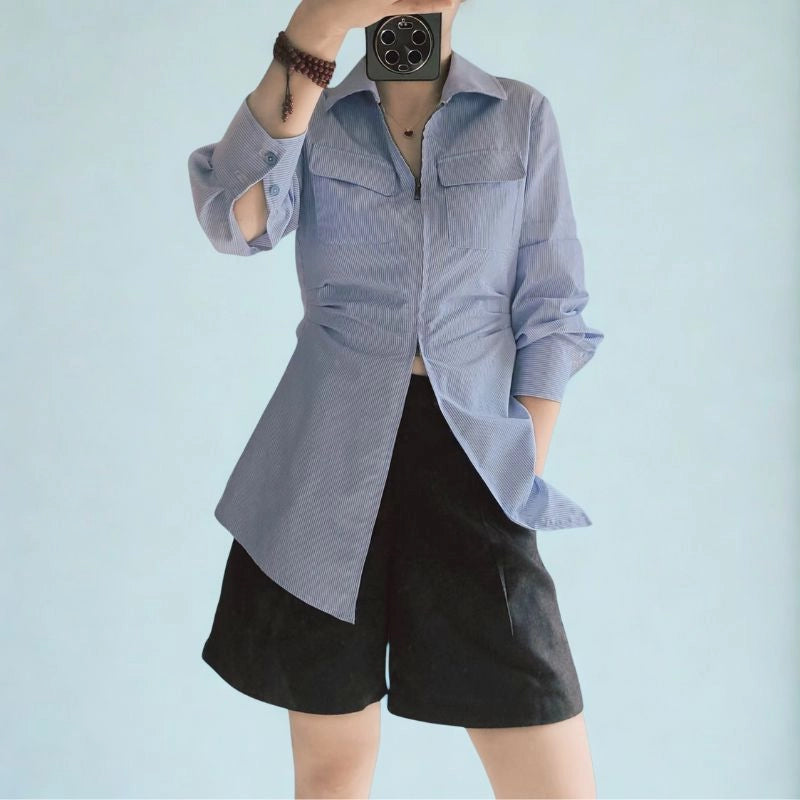 A person wears a light blue, long-sleeved shirt with front pockets and black shorts, standing against a matching background—perfect inspiration for sewing with the Longan Craft Women’s Zip-Front Shirt Sewing Pattern (Free PDF Download).