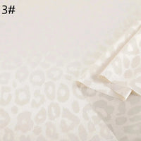 A close-up of Longan Craft's Leopard Jacquard Satin Fabric by the Yard, a soft and smooth multicolor polyester with a subtle glossy leopard print. The sample's zigzag edges and "3#" marking appear in the upper left corner.