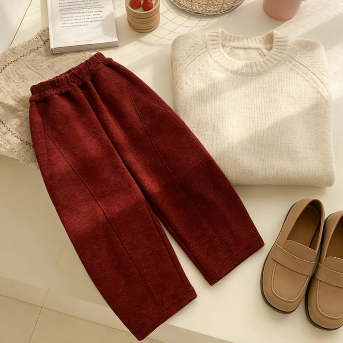 A cozy scene with maroon pants made using the Longan Craft Structured Pants Sewing Pattern (free PDF download), paired with a cream knit sweater and tan loafers, set against a backdrop of a woven mat, cup, and book on a light surface.