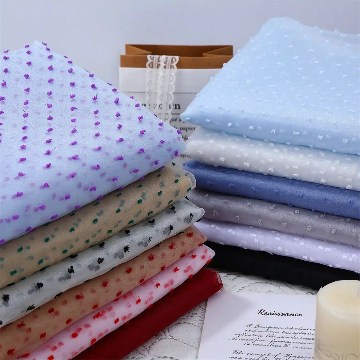 Two stacks of Sheer Swiss Dot Organza Fabric By The Yard featuring various colors of small, three-dimensional polka dots.