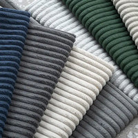 A close-up of Longan Craft's 2.5 Wale Multicolor Corduroy Fabric by the yard, neatly layered in a diagonal pattern, showcases its rich polyester texture ideal for upholstery and crafts.