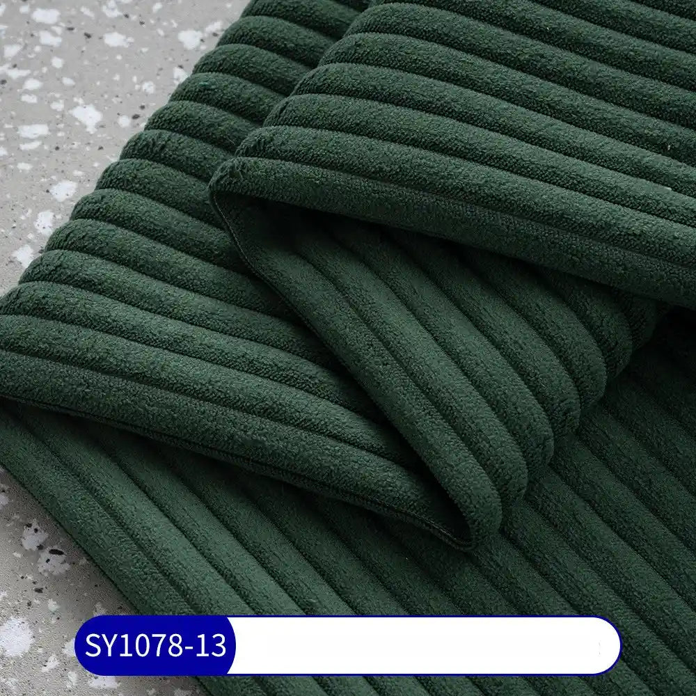 A close-up of Longan Craft's 2.5 Wale Multicolor Polyester Corduroy Fabric, neatly folded on a gray speckled surface, with a blue and white “SY1078-13” label—ideal Corduroy Upholstery Fabric by the yard for your next project.