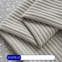 A close-up shows a folded light gray 2.5 Wale Corduroy Fabric by Longan Craft on a gray speckled surface, highlighting its corduroy texture. A label at the bottom reads SY1078-17 in white on blue.