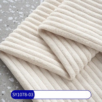 A close-up of a folded, cream-colored 2.5 Wale Corduroy Fabric by Longan Craft shows its soft, corduroy-like texture on a speckled gray surface. A blue and white SY1078-03 label is visible at the bottom left.