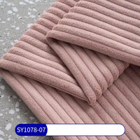 A close-up of folded, ribbed light mauve 2.5 Wale Corduroy Fabric By The Yard from Longan Craft on a gray speckled surface, with a blue SY1078-07 label. Made of multicolor polyester corduroy material for upholstery.