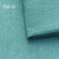 A close-up of Longan Craft Faux Linen Upholstery Fabric in teal shows its smooth, textured polyester surface. One piece is folded over another, with “158-21” printed in white at the upper left. Ideal for reupholstering chairs, sofas, or curtains.