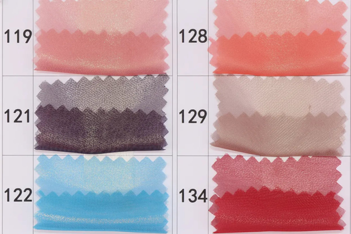 A chart displays six swatches of Longan craft Metallic Chiffon Fabric By The Yard in iridescent pink, purple, blue, coral, beige, and red (numbers 119, 121, 122, 128, 129, and 134)—perfect for dressmaking and sewing projects.