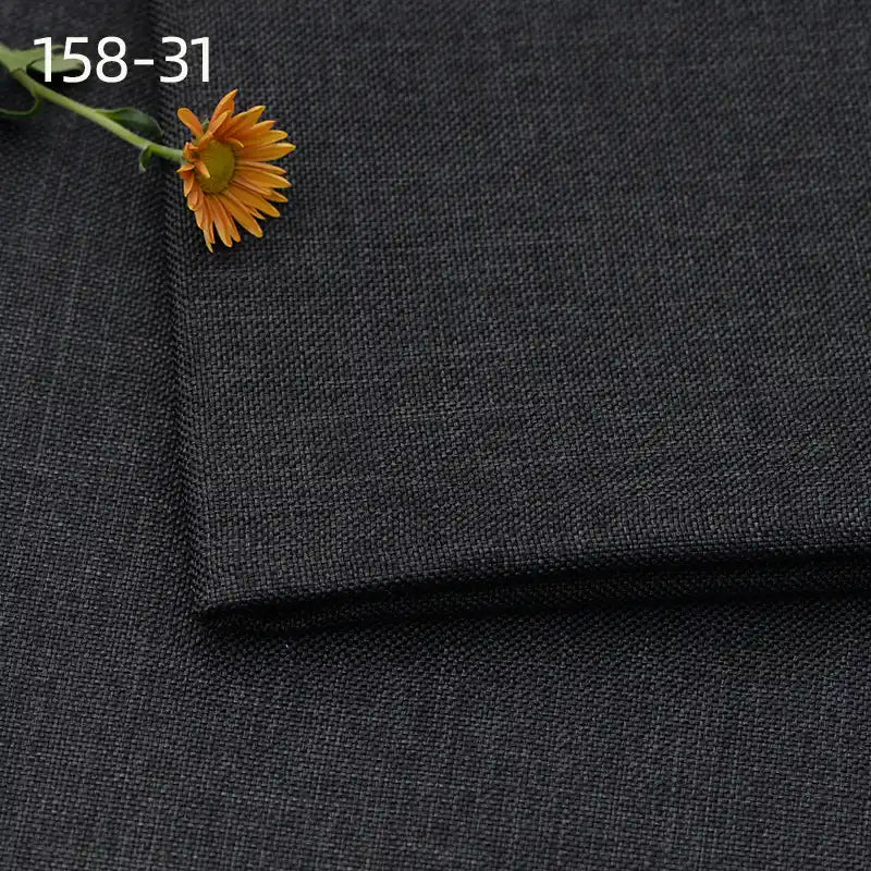 Longan Craft Faux Linen Upholstery Fabric By The Yard in dark gray is neatly folded with an orange daisy on top. "158-31" appears in white text at the upper left, showcasing this durable polyester fabric for reupholstering furniture.