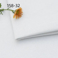 A folded piece of Longan Craft Faux Linen Upholstery Fabric in white, topped with a yellow daisy and green stem; "158-32" appears in the top left corner.