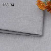 A close-up of Longan Craft’s faux linen upholstery fabric by the yard shows folded light gray polyester with woven texture. Orange flowers appear in the top right, and “158-34” is printed in black on the top left of the fabric.