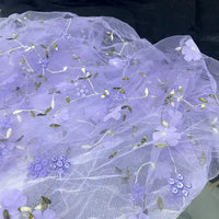 Longan Craft's 3D Floral Embroidered Tulle Fabric by the yard features colorful botanical embroidery—delicate purple flowers, green leaves, and gold accents—making it perfect bridal tulle material for romantic wedding dresses.