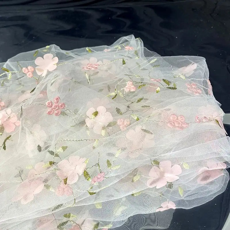 Longan Craft’s 3D Floral Embroidered Tulle Fabric by the yard features colorful botanical embroidery on white tulle, perfect for bridal gowns or special occasion dresses. This elegant material is ideal for unique and memorable creations.