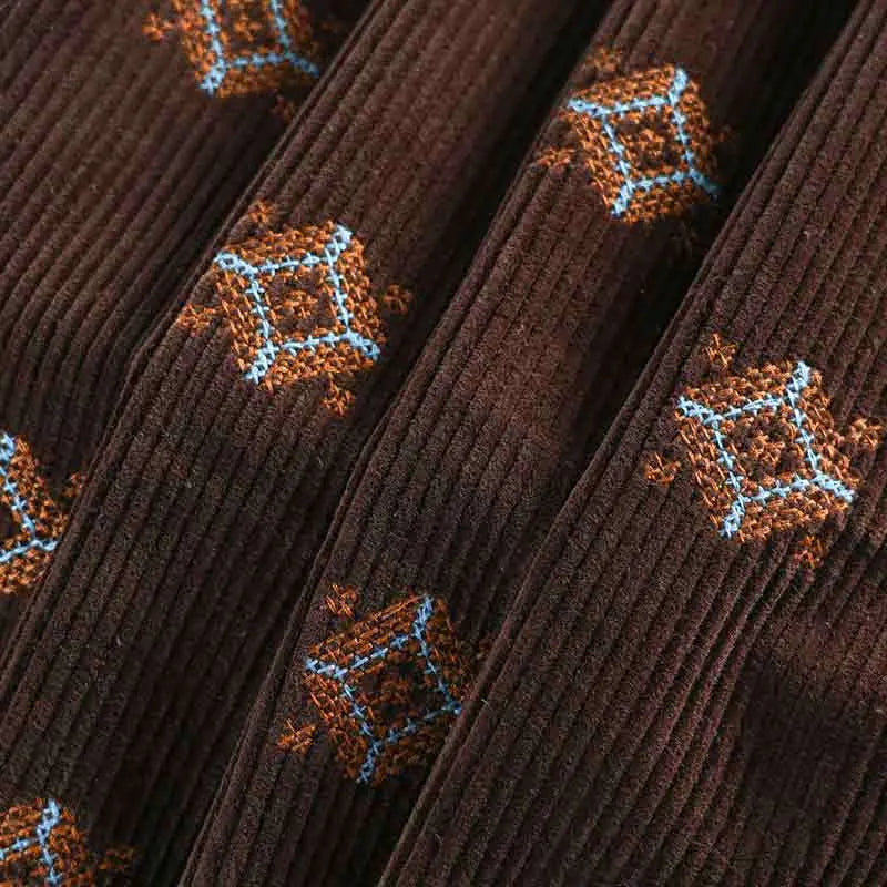 Close-up of Longan Craft 3D Patterned Embroidery Corduroy Fabric by the yard—fine wale cotton corduroy with orange-brown and blue embroidered diamonds; ideal, comfy material for jackets and clothing.