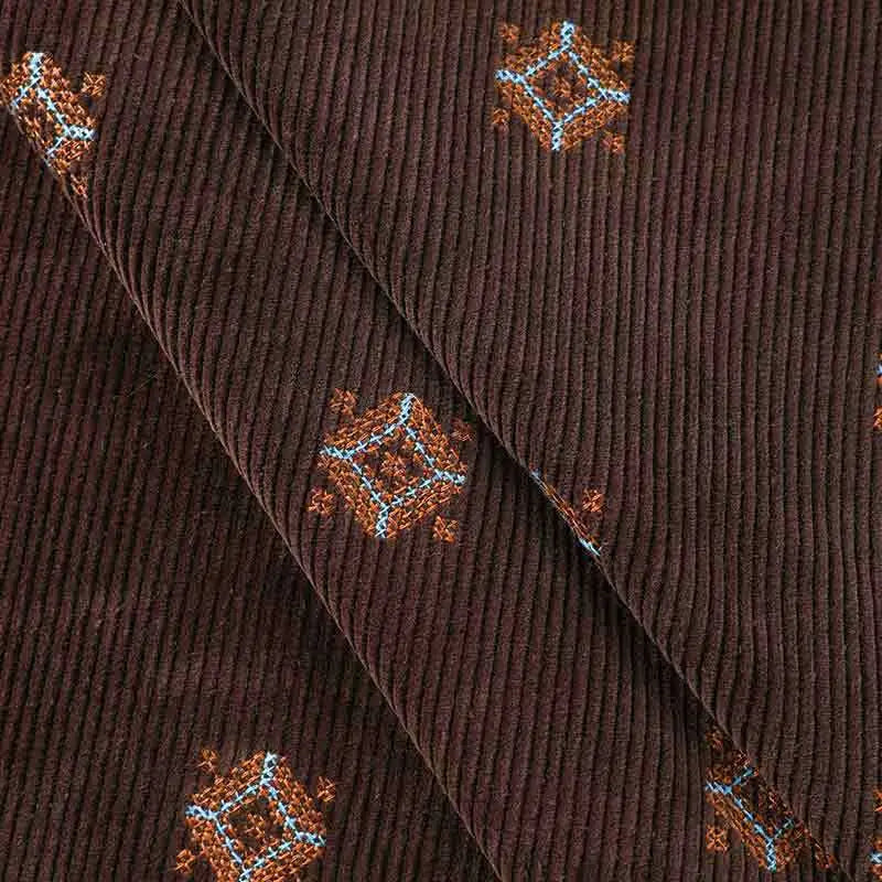 Close-up of Longan Craft’s 3D Patterned Embroidery Corduroy Fabric, a comfy fine wale cotton textile featuring subtle ribs and blue-orange geometric embroidery, perfect for clothing projects.