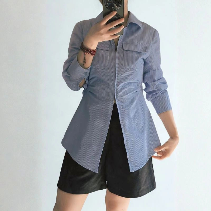 Wearing a light blue long-sleeve shirt and black shorts, she takes a mirror selfie—perfect inspiration for sewing your own with the Women’s Zip-Front Shirt Sewing Pattern by Longan Craft, available as a free PDF download.