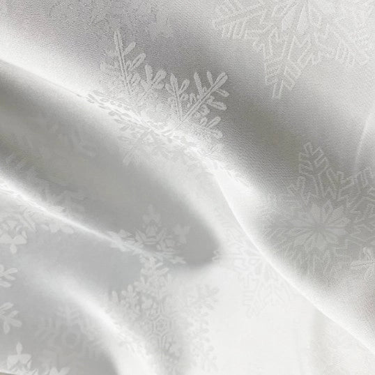 Longan Craft’s Snowflake Jacquard Satin Fabric by the yard features a subtle snowflake pattern on smooth white polyester satin—perfect for elegant dresses and crafts.